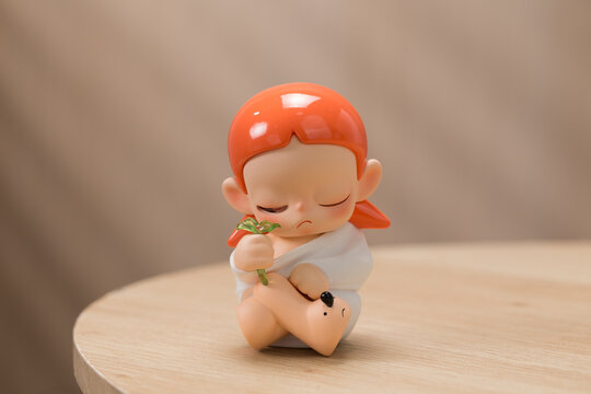 Pop Mart Zsiga Budding Life. An orange-haired doll was captured glancing at a miniature green tree held in its hand, amidst a warm and inviting domestic atmosphere.