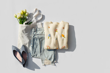Fashion spring outfit. White jumper with bouquet of tulips flowers in bag, blue jeans and ballet shoes. Women's stylish and elegant clothes with accessory and jewelry. Fashionable look.