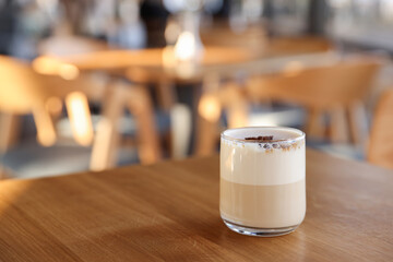 Glass of aromatic coffee on wooden table in cafe, closeup. Space for text