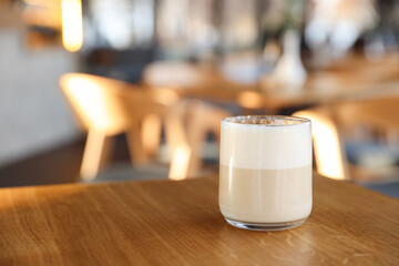 Glass of aromatic coffee on wooden table in cafe, closeup. Space for text
