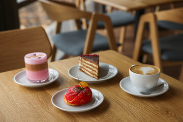 Aromatic coffee and delicious desserts served on wooden table in cafe