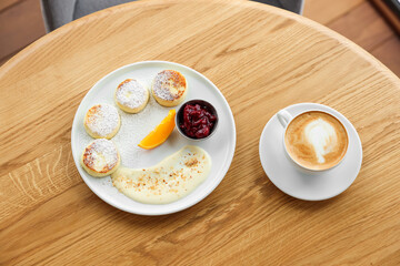 Delicious cottage cheese pancakes and coffee served on wooden table, top view