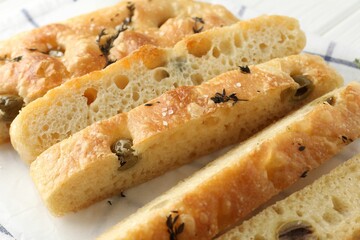 Slices of delicious focaccia bread with olives, thyme and salt on table, closeup
