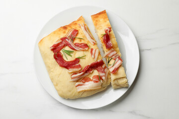 Pieces of delicious focaccia bread with bacon and rosemary on white marble table, top view