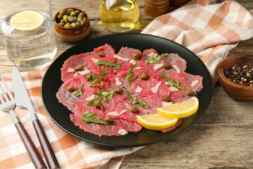 Delicious beef carpaccio served on wooden table, closeup