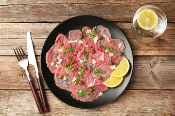Delicious beef carpaccio served on wooden table, flat lay