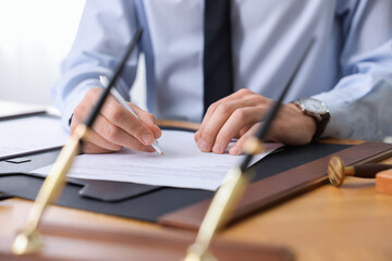 Notary signing document at table in office, closeup