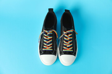 Black shoes with bright rainbow laces on light blue background, above view. LGBT concept