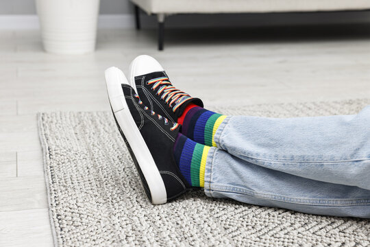 Man wearing socks in colors of LGBT flag on floor indoors, closeup
