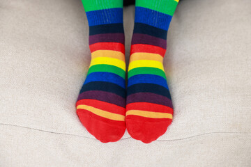 Woman wearing socks in LGBT colors on sofa indoors, closeup