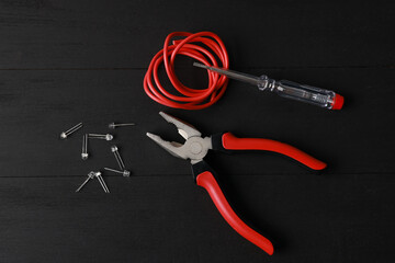Different electrical tools on black wooden table, flat lay