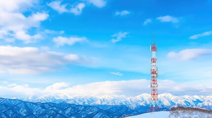 Obraz premium A tall communication tower stands against a backdrop of snow-capped mountains and a clear blue sky.