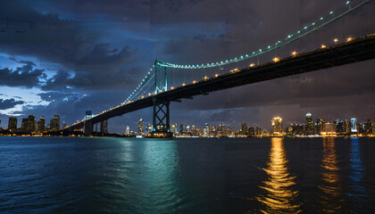 Fototapeta premium Le pont suspendu au-dessus du fleuve nocturne