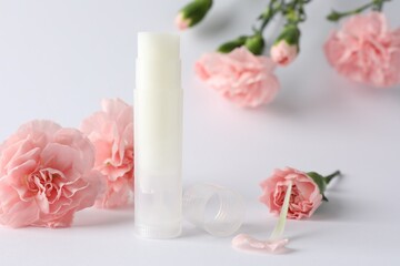 LIp balm and eustoma flowers on white background, closeup