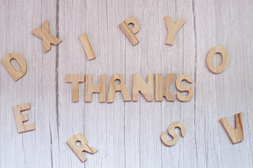 Overhead view of the word thanks made from wooden letters on a wooden table
