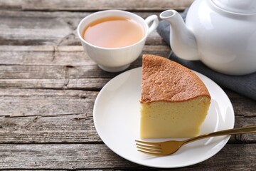 Tasty Japanese Castella sponge cake, tea and fork on wooden table, closeup. Space for text