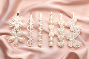Beautiful hair clips on pink silk fabric, flat lay
