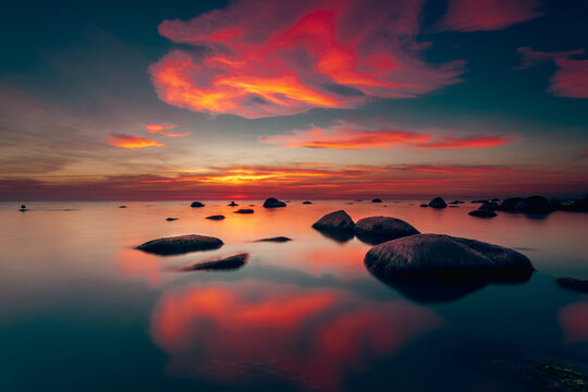Dramatic sunset with red clouds over rocks in the Baltic Sea, Lithuania