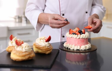 Professional pastry chef making cake at table in kitchen, closeup