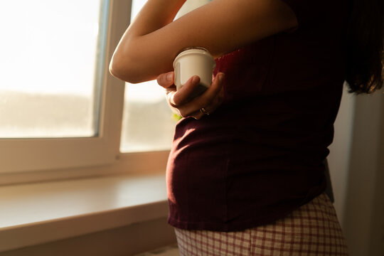 Close-up of a woman standing by a window attaching a continuous glucose monitoring on her arm
