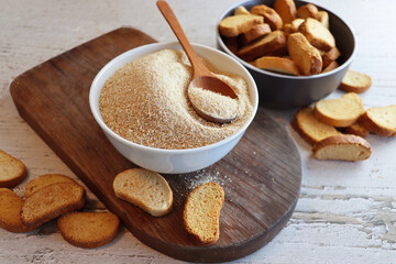Heap of Bread Crumbs in White Bowl Top View. Crushed Rusk Bread Crumbs on Wood Table