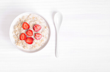 Tasty oatmeal with strawberry slices in bowl