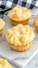 Fototapeta premium Delicious golden muffins on marble board, breakfast pastries, close-up shot, checkered cloth background, perfect for recipe blogs
