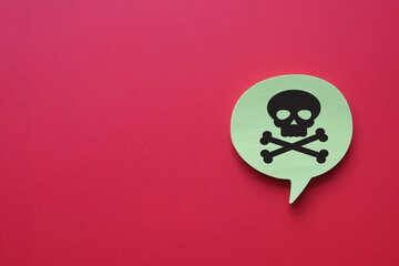 A warning sign with a poison skull and crossbones symbol inside a speech bubble on a bright red background representing danger, toxicity,alerting, hazardous materials,warning sign.