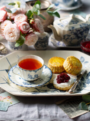Scones with jam, clotted cream and cup of tea. Flower background.