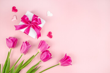 beautiful tulips with gift box hearts on a light pink background. happy mothers day, top view. copy space