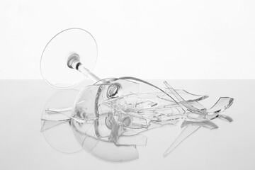 Pieces of broken wine glass on table against white background, closeup