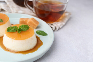 Tasty puddings with caramel sauce served on white table, closeup. Space for text