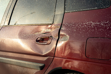Red car door dented after accident, car hit. Impact damage. Damaged rear door of car, dent after road collision