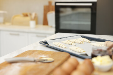 Raw croissants and ingredients on white table in kitchen, selective focus