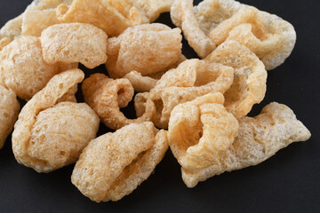 チチャロン　メキシコやフィリピンで食べられる豚の皮（豚皮）のスナック　コピースペースあり　黒背景 Chicharon　(chicharrón, chicharron), pork skin (pig skin) snack, eaten in Mexico and the Philippines, copy space available, black background