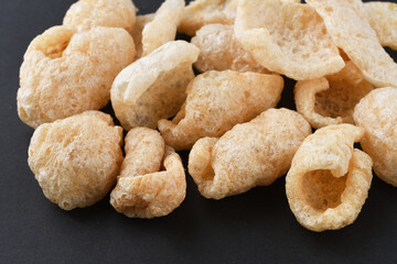 チチャロン　メキシコやフィリピンで食べられる豚の皮（豚皮）のスナック　コピースペースあり　黒背景 Chicharon　(chicharrón, chicharron), pork skin (pig skin) snack, eaten in Mexico and the Philippines, copy space available, black background