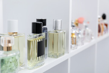 Different bottles of luxury perfume on shelf in store, closeup