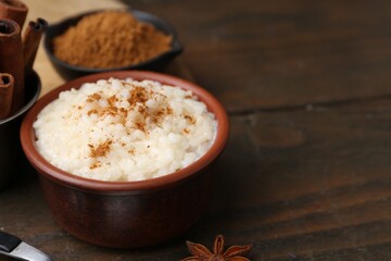 Tasty rice pudding with cinnamon served on wooden table, closeup. Space for text