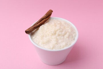 Tasty rice pudding with cinnamon on pink background, closeup