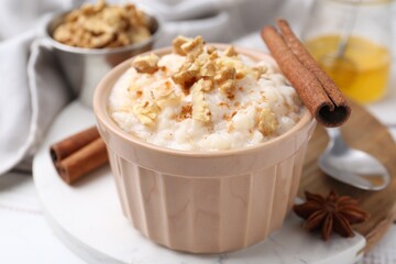 Tasty rice pudding with cinnamon served on white wooden table, closeup