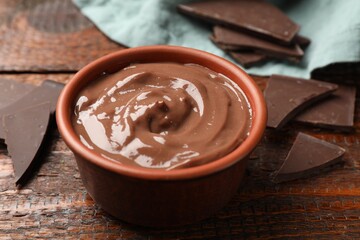 Tasty pudding and pieces of chocolate on wooden table, closeup
