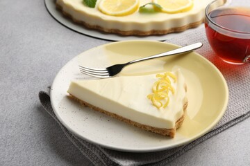 Piece of tasty lemon cheesecake on grey textured table, closeup