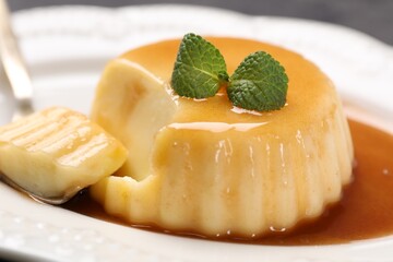 Delicious pudding with caramel sauce and mint served on table, closeup