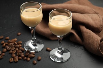 Coffee cream liqueur in glasses and beans on black table