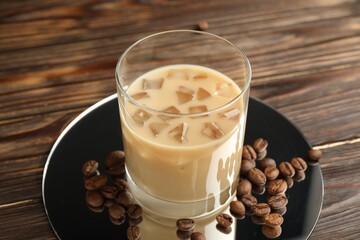 Coffee cream liqueur in glass and beans on wooden table, closeup