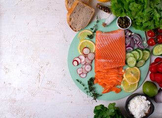 Salted trout fillet on green board surrounded by ingredients for making appetizer. Healthy eating. Top view. Copy space