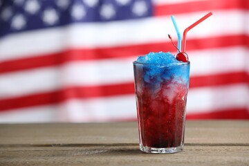 Tasty cocktail in glass on wooden table against flag of USA, space for text