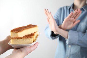 Woman refusing cheesecake on white background, , selective focus. Food allergy concept