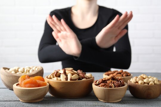 Woman refusing to eat products at grey wooden table, selective focus. Food allergy concept - Powered by Adobe