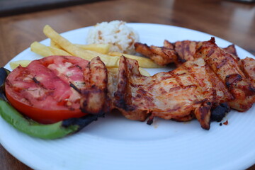 Grilled chicken with rice, french fries, roasted tomatoes and peppers